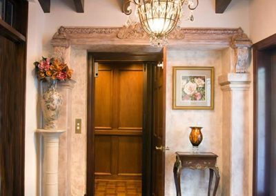 A foyer with a wooden door and a chandelier.