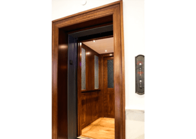 A wooden elevator with the door open.