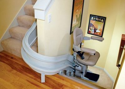 A curved stair lift in the corner of a room.