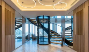 Modern spiral staircase with glass elevator in a spacious, well-lit interior.