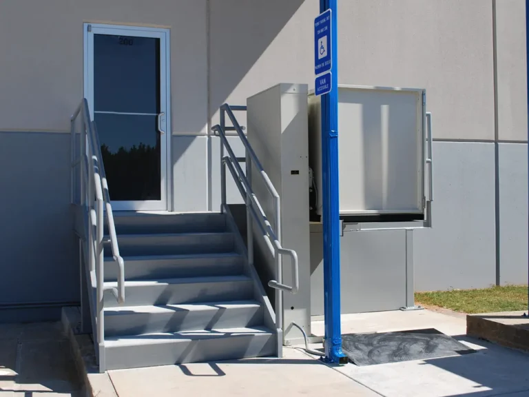 A wheelchair ramp and stairs with handrails leading to a building entrance.